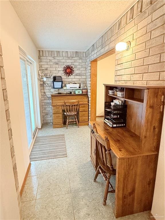 tiled home office with a textured ceiling and brick wall