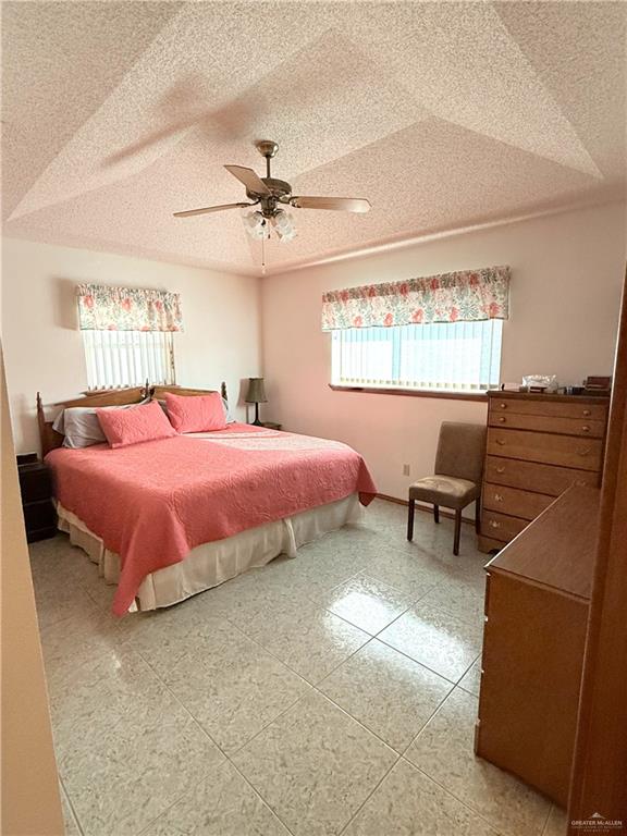 tiled bedroom featuring ceiling fan and a textured ceiling