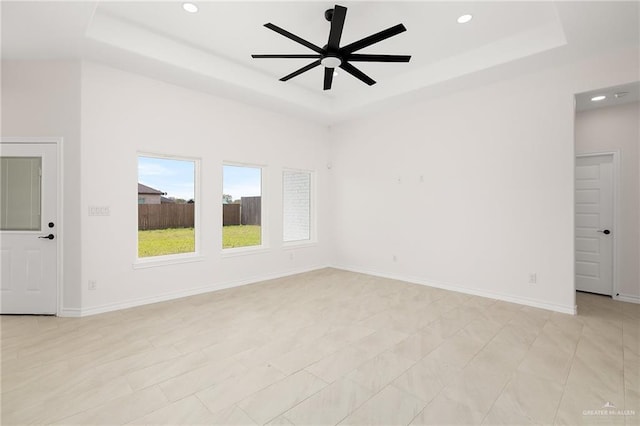 empty room with recessed lighting, a tray ceiling, baseboards, and ceiling fan