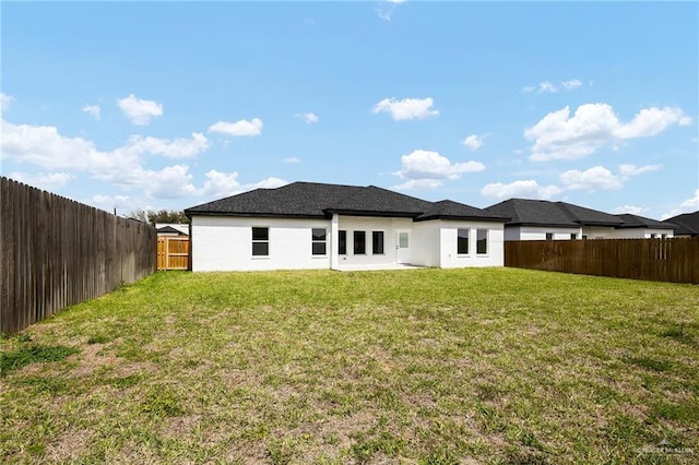 rear view of house featuring a lawn and a fenced backyard