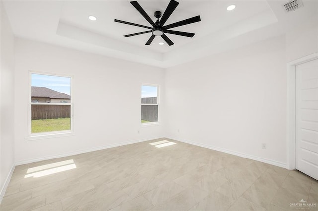 unfurnished room with visible vents, baseboards, a tray ceiling, recessed lighting, and a ceiling fan