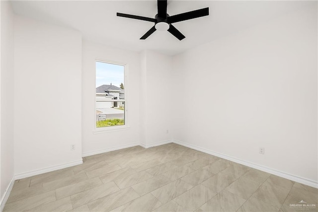 empty room with ceiling fan and baseboards