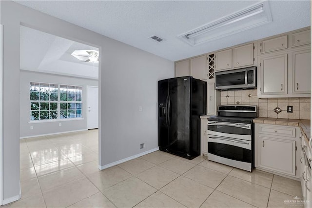 kitchen featuring ceiling fan, stainless steel appliances, light tile patterned floors, and backsplash