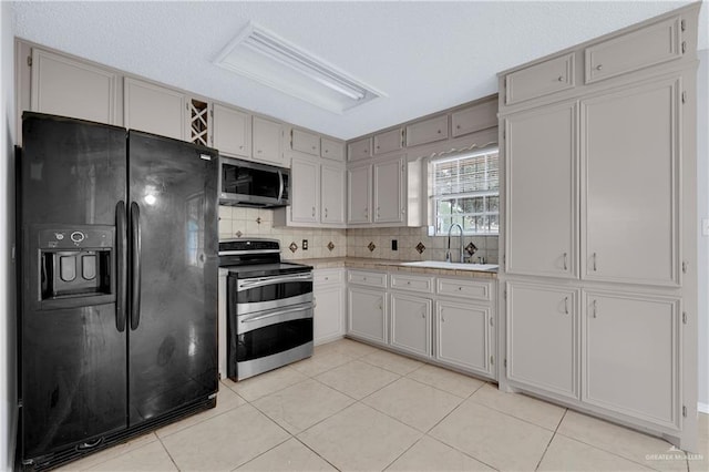 kitchen featuring tasteful backsplash, appliances with stainless steel finishes, sink, and light tile patterned floors