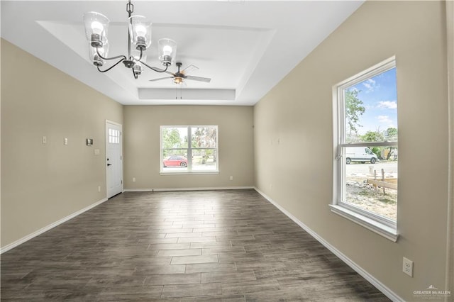 spare room featuring a tray ceiling, plenty of natural light, and dark hardwood / wood-style floors