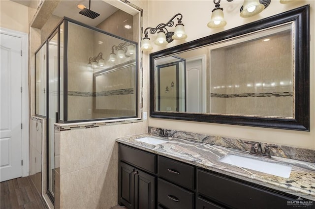 bathroom with hardwood / wood-style floors, vanity, and a shower with shower door