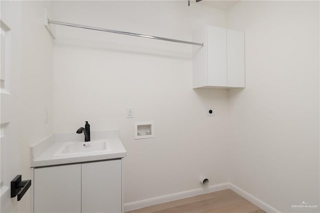 washroom featuring baseboards, hookup for a washing machine, a sink, hookup for an electric dryer, and cabinet space