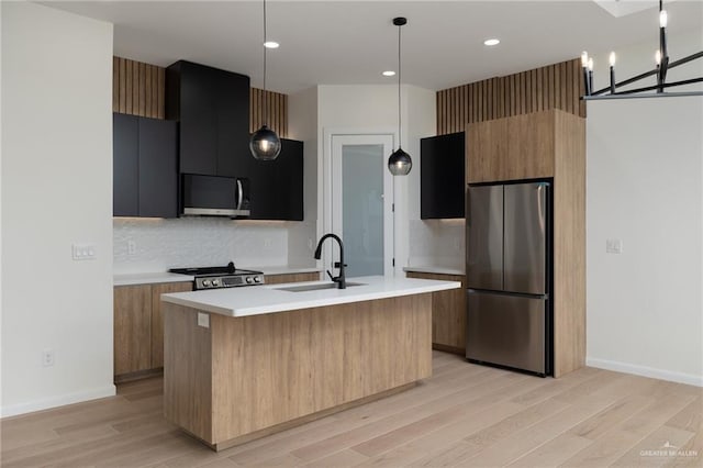kitchen featuring appliances with stainless steel finishes, modern cabinets, a sink, light countertops, and light wood-type flooring