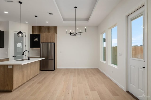 kitchen with freestanding refrigerator, light wood-style flooring, modern cabinets, a sink, and light countertops