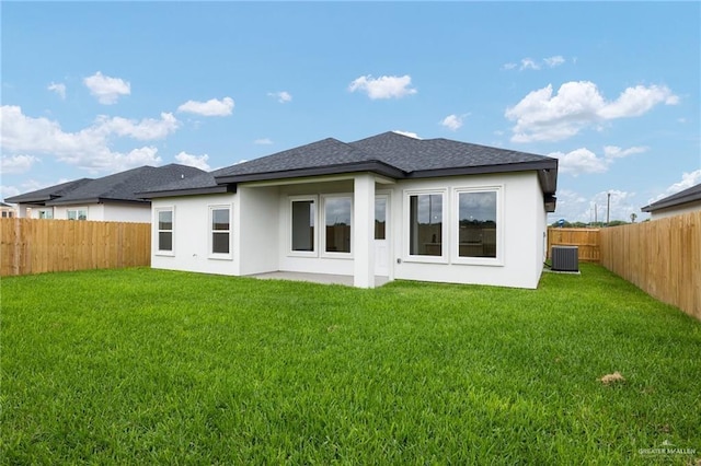 rear view of property featuring a yard, central AC unit, roof with shingles, and a fenced backyard