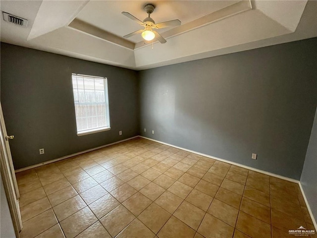 unfurnished room with visible vents, a raised ceiling, baseboards, ceiling fan, and tile patterned floors