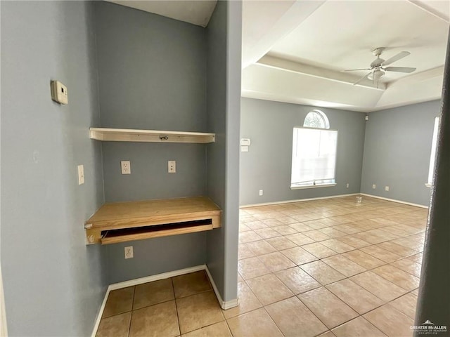 empty room featuring ceiling fan, a tray ceiling, tile patterned flooring, and baseboards