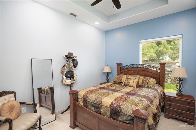 bedroom with light carpet, a raised ceiling, and ceiling fan