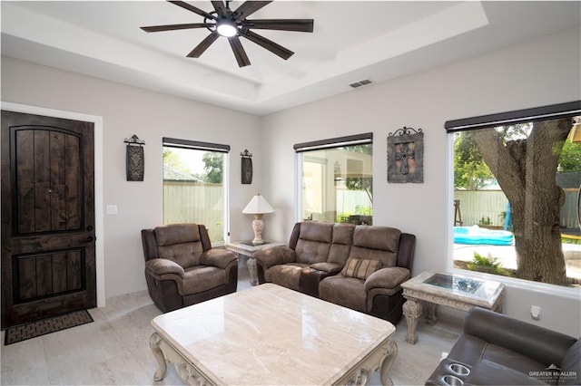 living room with a raised ceiling and ceiling fan