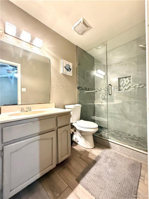 bathroom featuring vanity, toilet, and a shower with shower door