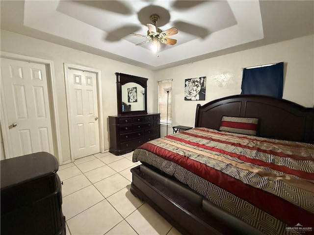 tiled bedroom with a raised ceiling and ceiling fan