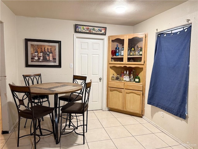 tiled dining room featuring a textured ceiling and indoor bar