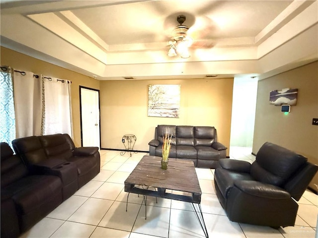 tiled living room featuring ceiling fan and a raised ceiling