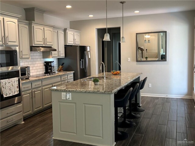10228 N 14th St, Mcallen, TX 78504 - kitchen with stainless steel appliances, under cabinet range hood, dark wood-style flooring, a breakfast bar area, and recessed lighting