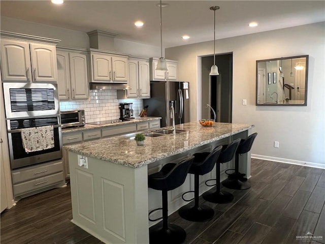 10228 N 14th St, Mcallen, TX 78504 - kitchen featuring appliances with stainless steel finishes, dark wood-type flooring, a kitchen bar, a center island with sink, and recessed lighting