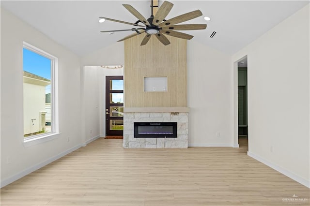 unfurnished living room with a fireplace, light wood-type flooring, vaulted ceiling, and a healthy amount of sunlight