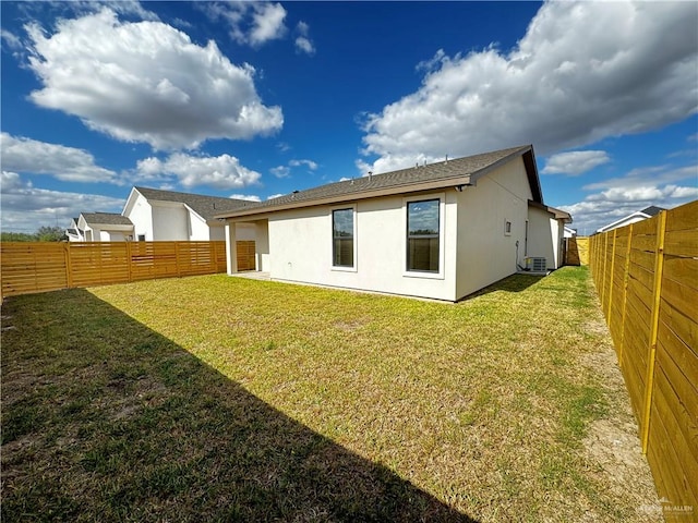 rear view of property featuring a yard and central air condition unit