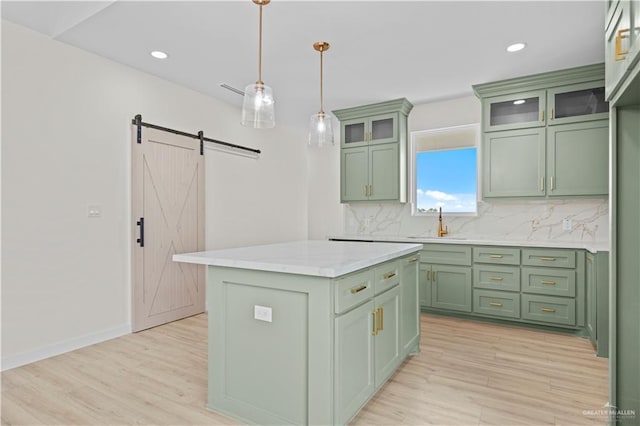 kitchen with a barn door, a center island, green cabinets, and hanging light fixtures