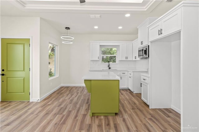 kitchen with pendant lighting, a kitchen island, white cabinetry, and light hardwood / wood-style flooring