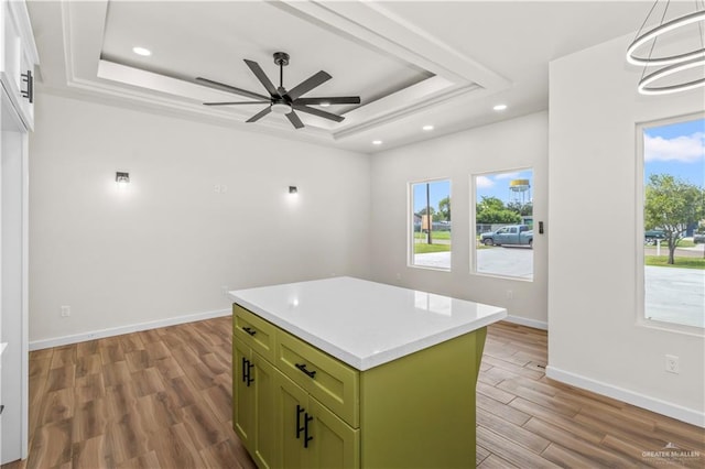 kitchen with a tray ceiling, a kitchen island, and light wood-type flooring