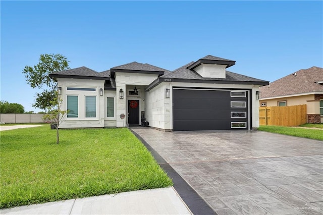 prairie-style house with fence, a shingled roof, a garage, a front yard, and concrete driveway