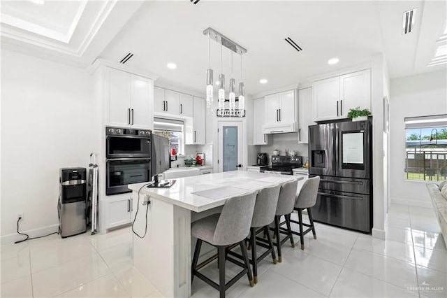 kitchen featuring light tile patterned floors, a kitchen island, stainless steel appliances, and under cabinet range hood