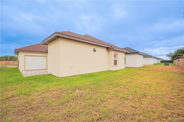 rear view of property with a garage and a lawn