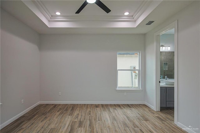 unfurnished room featuring hardwood / wood-style floors, a tray ceiling, and ceiling fan