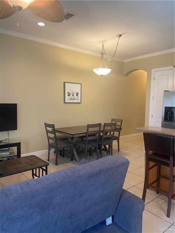 tiled dining area featuring ceiling fan and ornamental molding