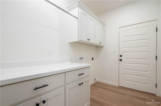 clothes washing area featuring cabinets, light hardwood / wood-style floors, washer hookup, and hookup for an electric dryer