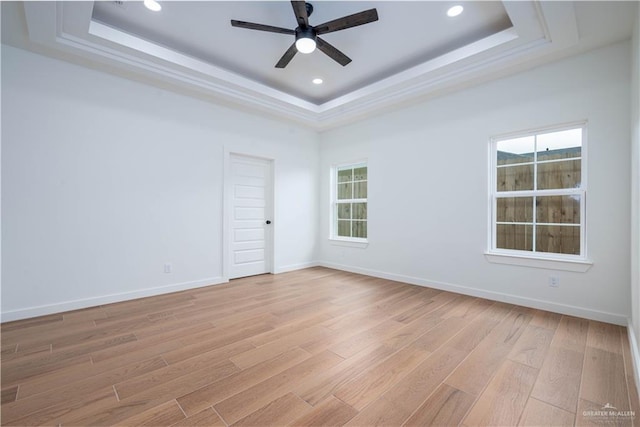 unfurnished room featuring ceiling fan, a raised ceiling, and light hardwood / wood-style flooring