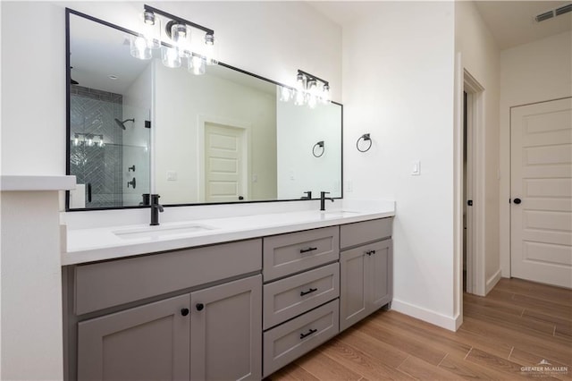 bathroom featuring tiled shower, hardwood / wood-style floors, and vanity