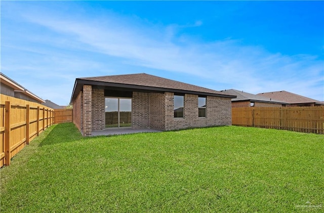 rear view of house featuring brick siding, a fenced backyard, a lawn, and a patio