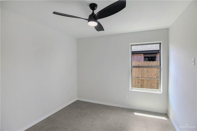 tiled spare room featuring baseboards and a ceiling fan