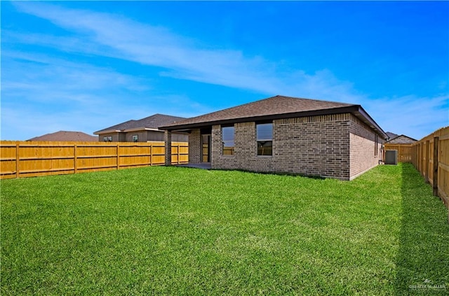 rear view of house with a lawn, brick siding, a shingled roof, and a fenced backyard