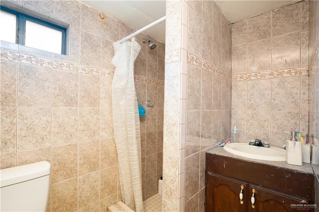 bathroom with vanity, tile walls, toilet, and walk in shower