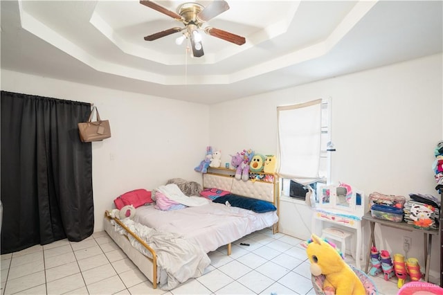 bedroom with a raised ceiling, ceiling fan, and light tile patterned flooring