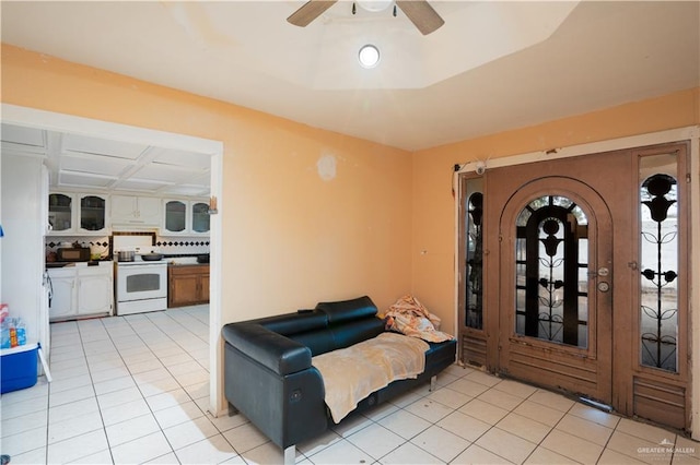 living room featuring coffered ceiling, light tile patterned floors, and ceiling fan