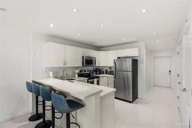 kitchen with kitchen peninsula, sink, a breakfast bar, and appliances with stainless steel finishes