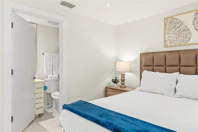 bedroom with ensuite bathroom and light tile patterned floors