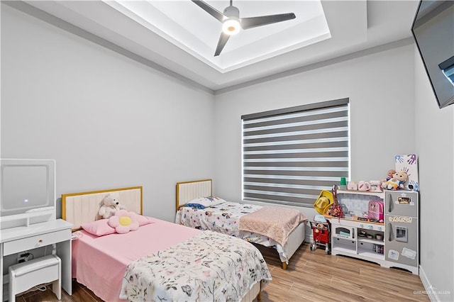 bedroom featuring wood-type flooring, a tray ceiling, and ceiling fan