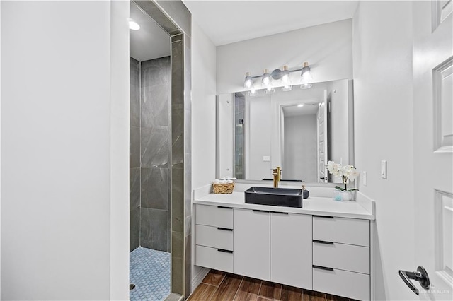 bathroom with hardwood / wood-style floors, vanity, and tiled shower