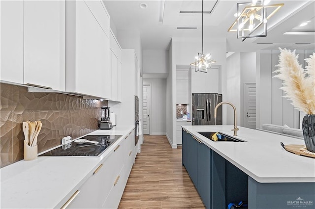 kitchen with sink, appliances with stainless steel finishes, decorative light fixtures, white cabinetry, and a chandelier