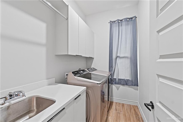 laundry area with washer and dryer, cabinets, light wood-type flooring, and sink