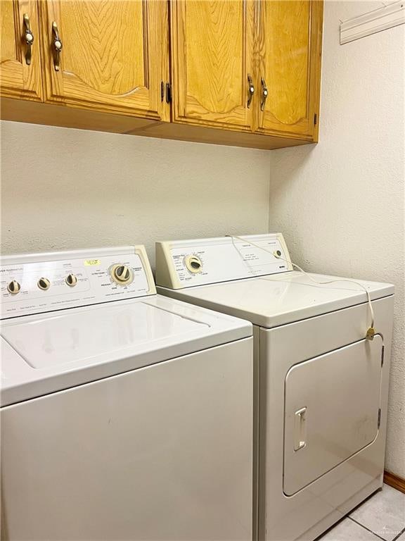 washroom with washer and dryer, cabinets, and light tile patterned floors